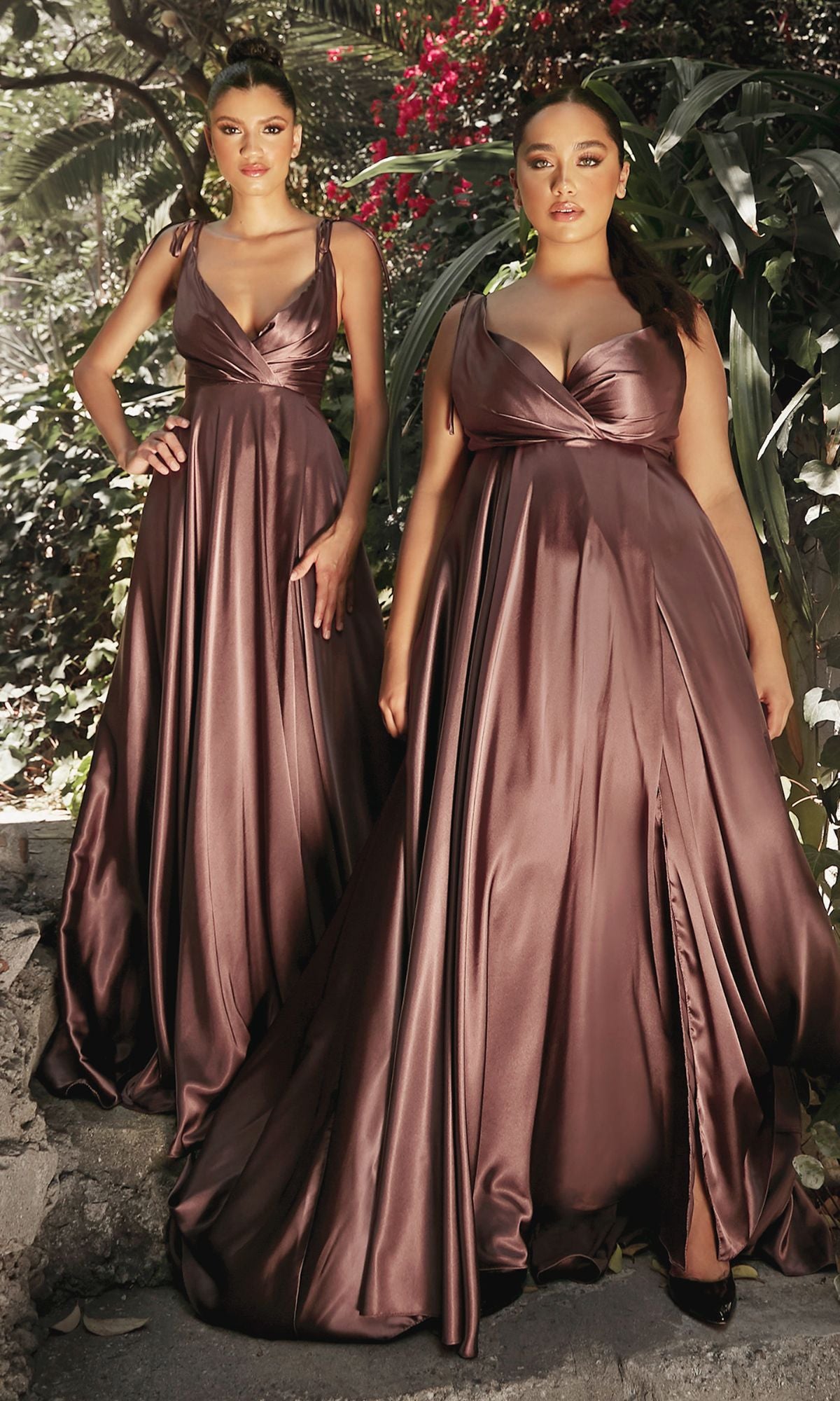 Two women outdoors wear matching Shoulder-Tie Long Satin V-Neck Prom Dress BD105, featuring elegant floor-length silhouettes. Lush greenery and vibrant red flowers form a beautiful backdrop for their stunning look.